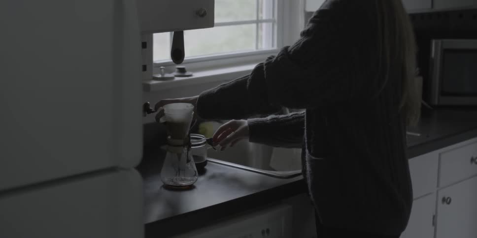 A woman makes coffee in a kitchen