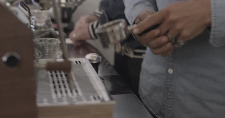 A man tampers some coffee grounds while making espresso
