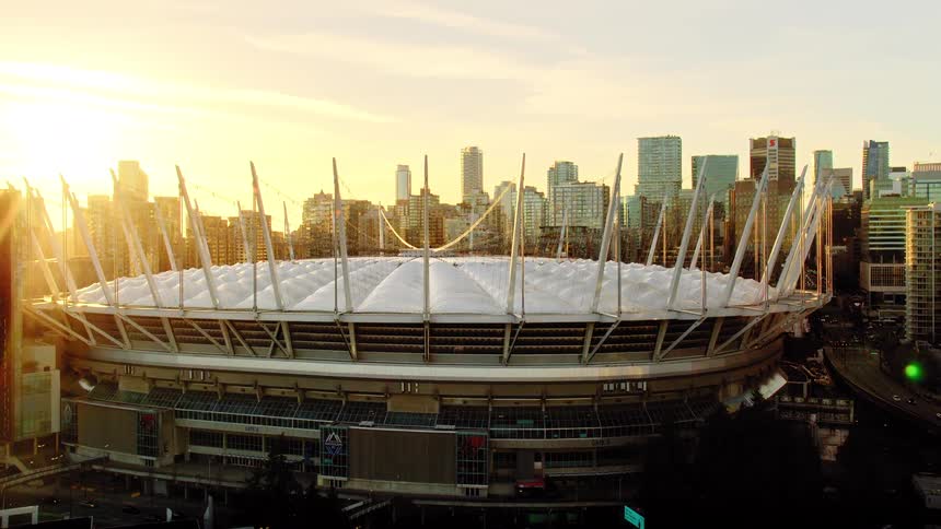 A stunning aerial reveal of BC Place Stadium and the Vancouver cityscape glowing in the warm light of sunset