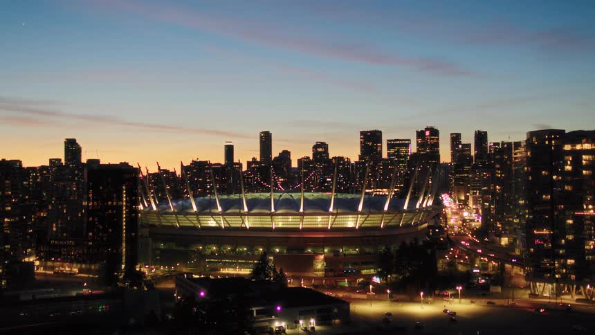 A slow, cinematic pullback reveals the iconic BC Place stadium and the dazzling Vancouver city skyline at twilight