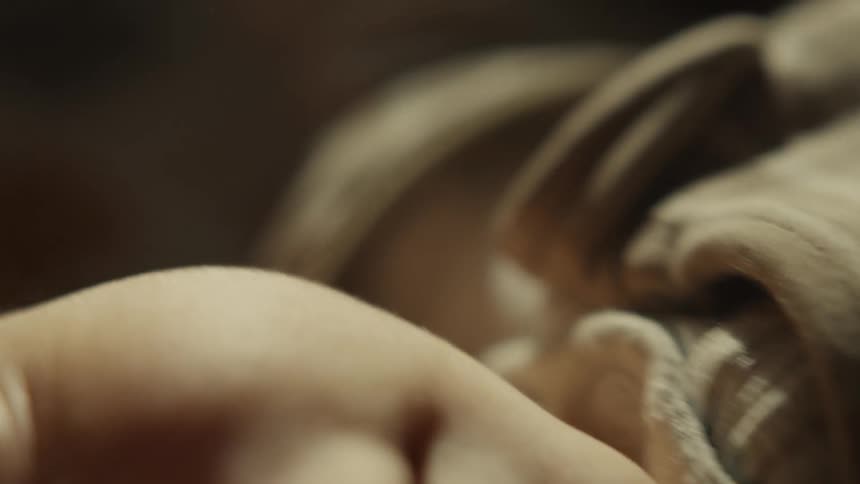 A tender, extreme close-up of a newborn baby's face, focusing on their curious eye looking around in soft, warm light