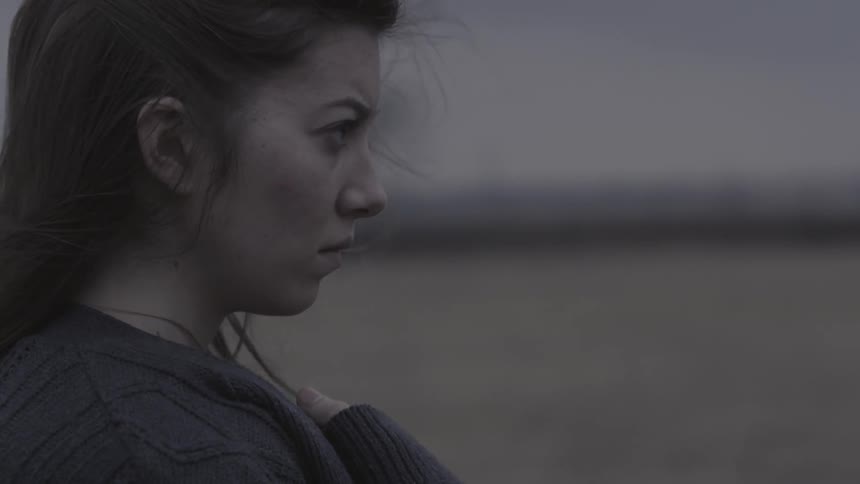 A woman stands outside on a windy and overcast day