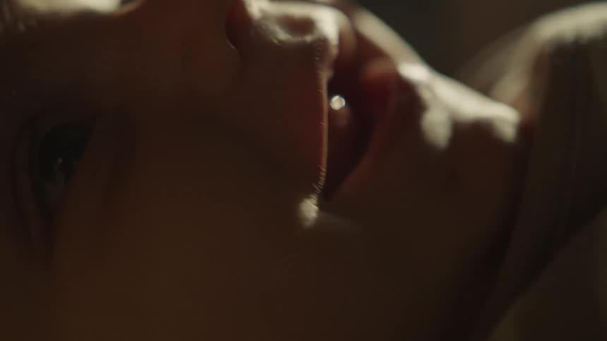 An intimate extreme close-up of a newborn baby's face as they sleep peacefully in soft, warm light