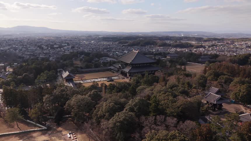 Stationary aerial shot captures the majestic Todai-ji Temple complex in Nara, Japan, nestled in a park overlooking the city