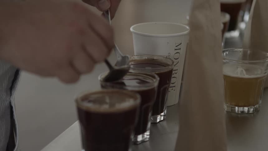 A man is spooning some coffee with two spoons