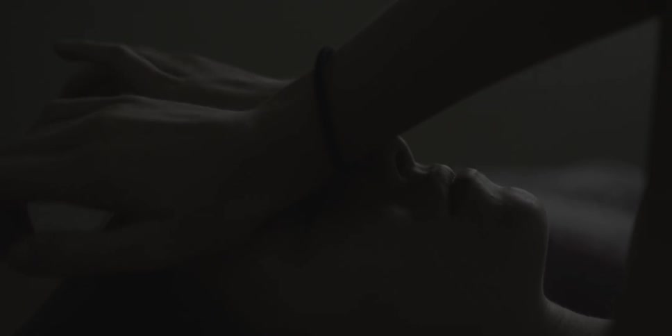 A woman touches her forehead while laying in bed