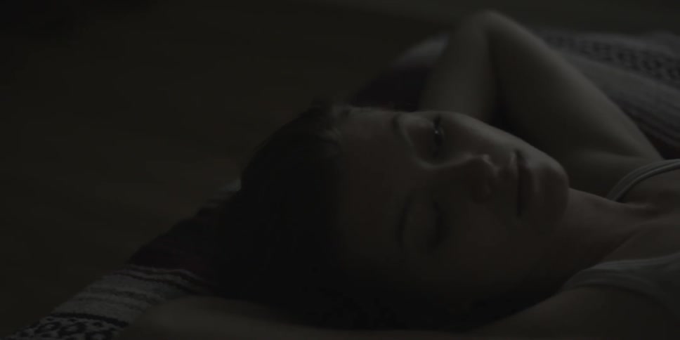 A woman lies on her back with her hands behind her head