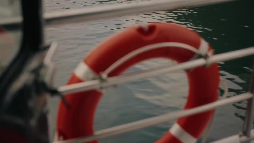 Out-of-focus shot of a red lifebuoy attached to a boat railing as it moves through the water