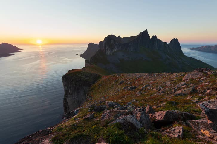 A majestic timelapse from a clifftop vantage point captures the sun setting behind the dramatic Devil's Jaw mountains of Senja Island in Norway