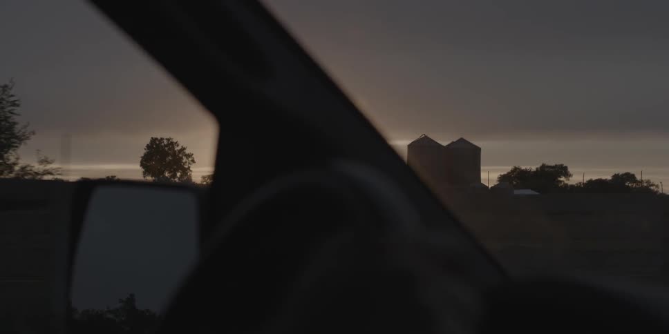 A car is traveling down the road at dawn