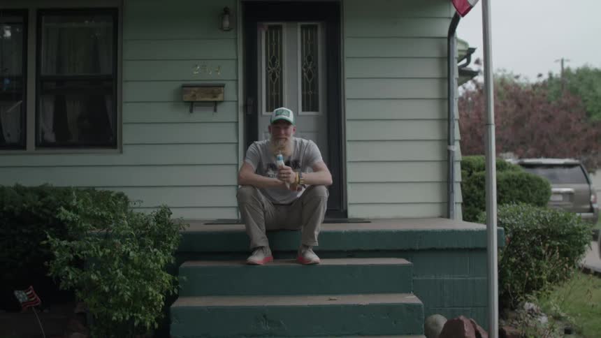 A man sits on the porch eating some ice cream