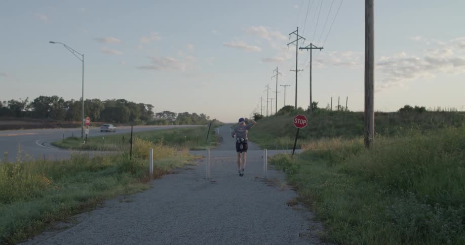 A person jogs down a trail by a road