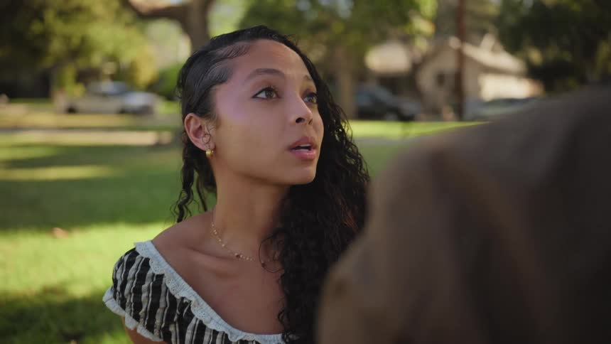Close up of a young woman's face as she listens and smiles during an outdoor conversation in a park