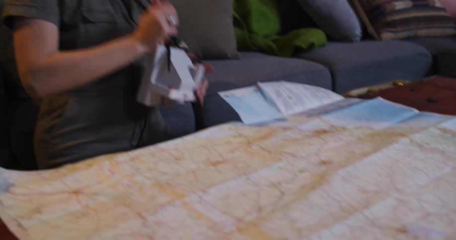 An adventurous woman dressed as a traveler lays out a large map in slow motion to plan her next big trip