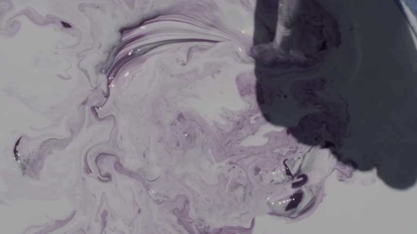 Artist mixes dab of purple paint into large areas of white paint