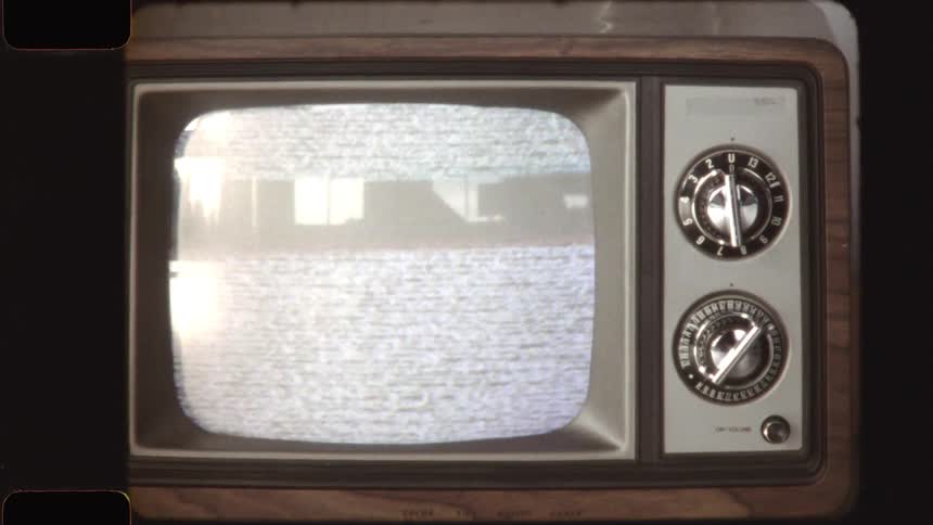 A retro-style wooden television set displays flickering static noise, framed by a vintage film border