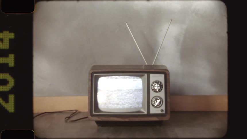 A retro television set displays flickering static noise with a vintage 8mm film effect