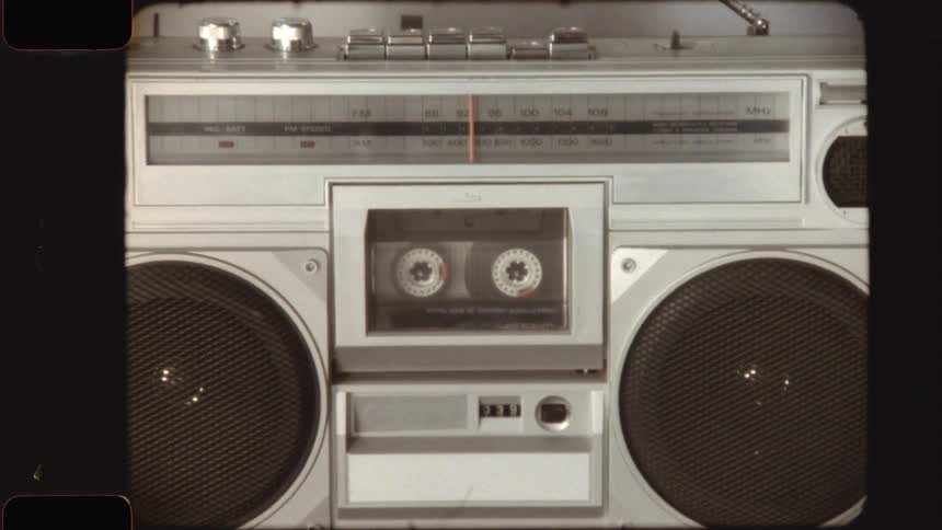 A retro film-style video zooms out from a cassette tape playing to reveal a vintage boombox