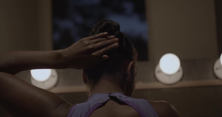 Woman putting bobby pins in her hair in room at night