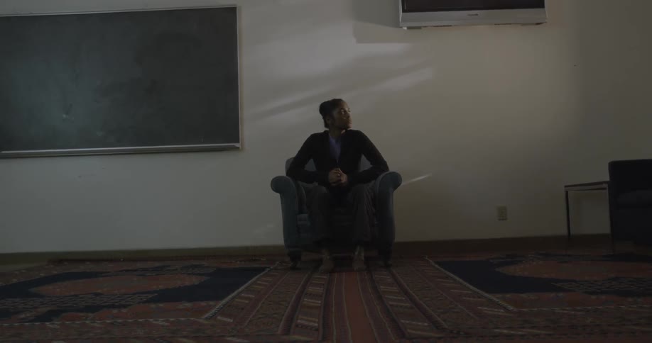A person sitting on a recliner in a room next to a chalkboard