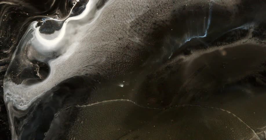 Mesmerizing abstract patterns form as white ink slowly flows and expands through a dark, viscous liquid