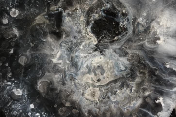 Eerie and abstract swirling patterns of black and white ink create a cosmic, otherworldly landscape