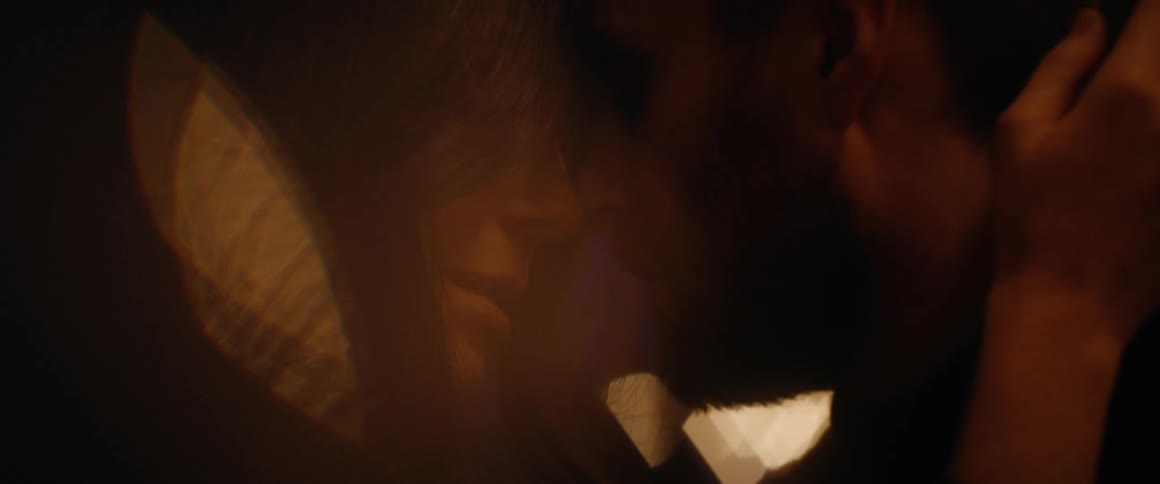 An intimate close-up of a romantic couple embracing and touching foreheads in warm, atmospheric lighting