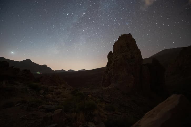 A beautiful time-lapse of the Milky Way and shooting stars moving across the night sky above dramatic volcanic rock formations