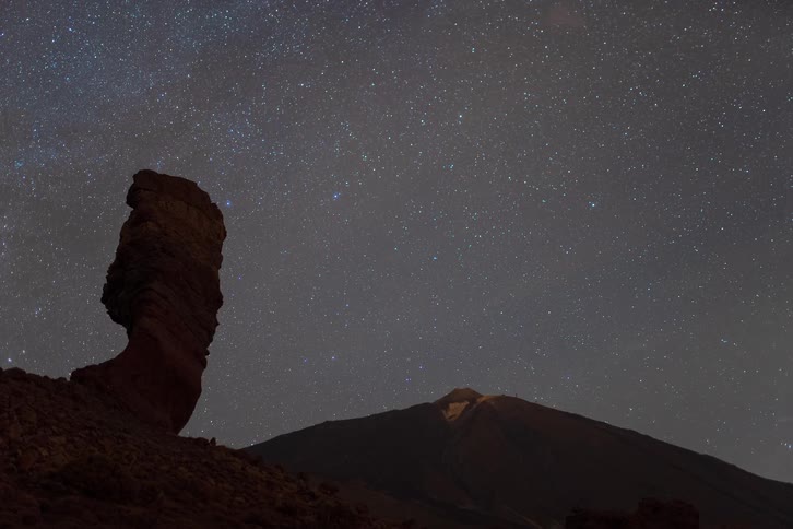 A stunning astrophotography timelapse of the stars rotating in the night sky over a majestic mountain and rock formation