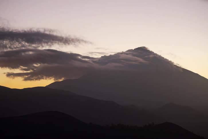 Timelapse of dramatic clouds flowing over a mountain silhouette during a beautiful sunset