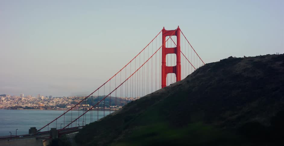 A scenic drive-by shot of the iconic Golden Gate Bridge with the San Francisco skyline across the bay