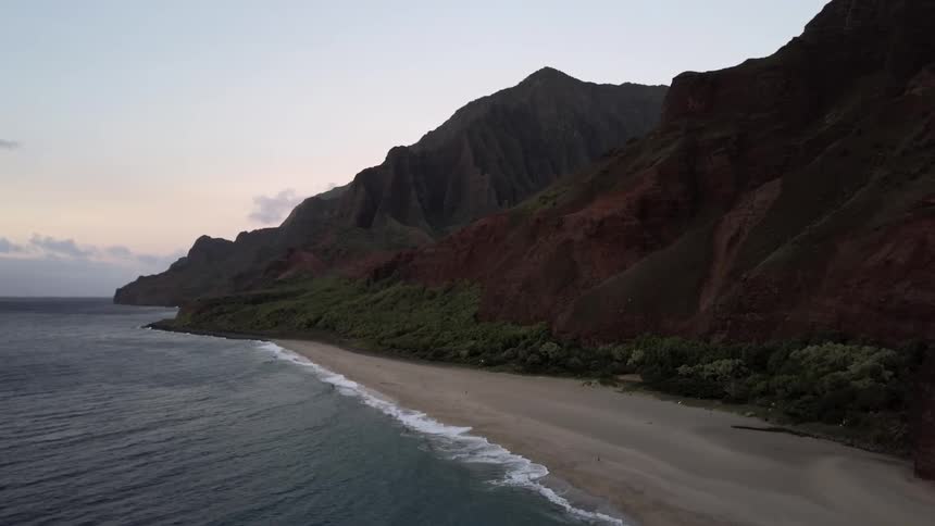 Waves rolling onto a beach next to mountains