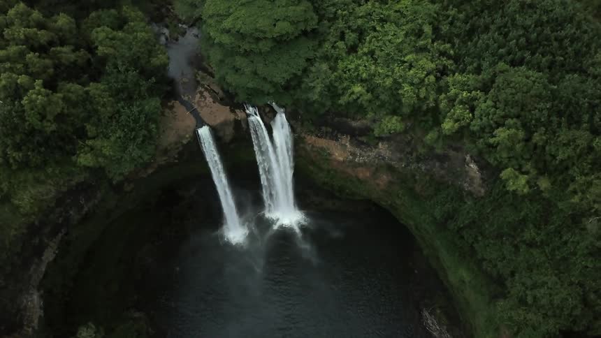 Three waterfalls flow into a pond a the base of a cliff