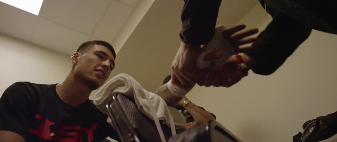 A man bandaging a young man's hand as another man watches
