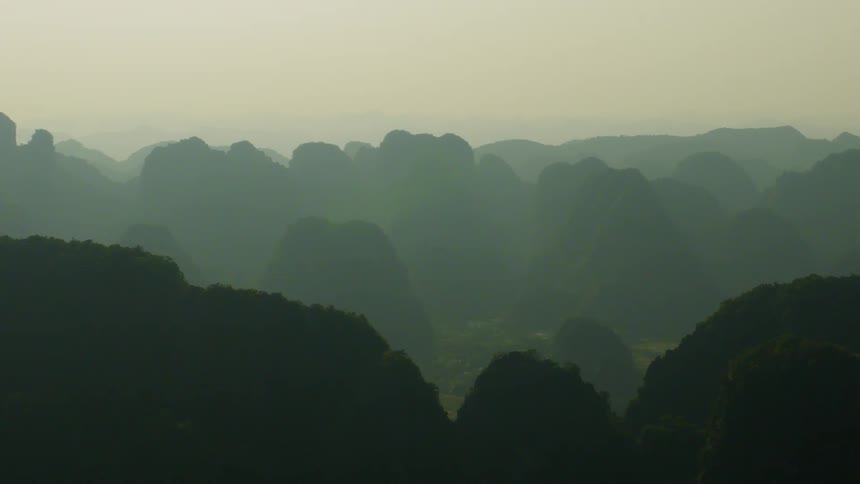 A vast and hazy mountain range stretches across the horizon under the soft morning light