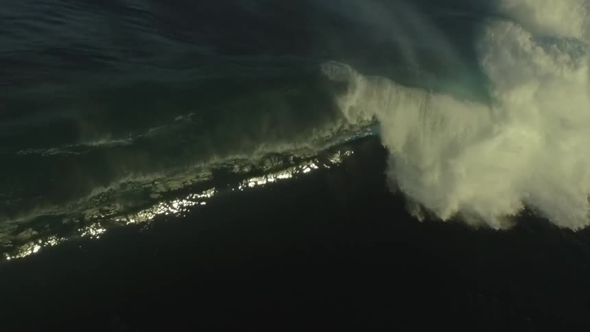 A massive, dark ocean wave builds and crashes in dramatic, mesmerizing slow motion
