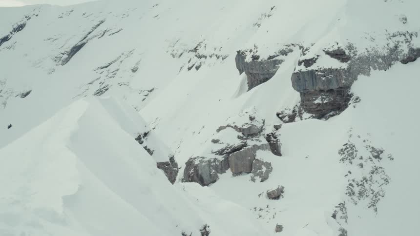 Cinemagraph loop of a vast, snow-covered mountain landscape on a cold, overcast day