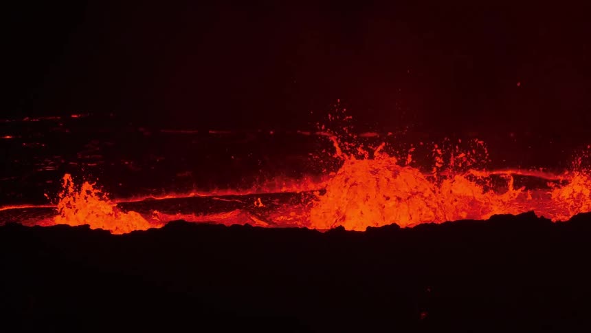 A mesmerizing slow-motion close-up captures the violent eruption of a volcano at night as molten lava bubbles and explodes