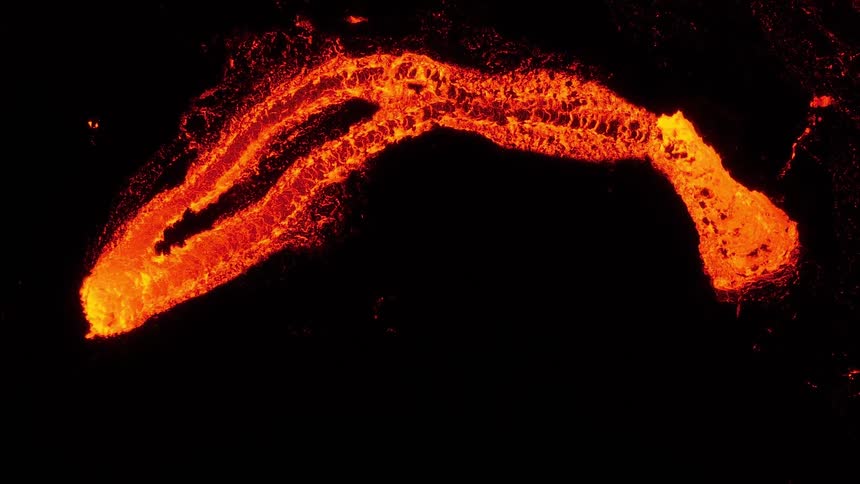 An intense top-down aerial view of a vibrant orange lava river flowing slowly in a continuous loop