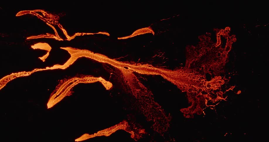 A mesmerizing top-down aerial view of a fiery orange river of lava flowing across a dark volcanic landscape