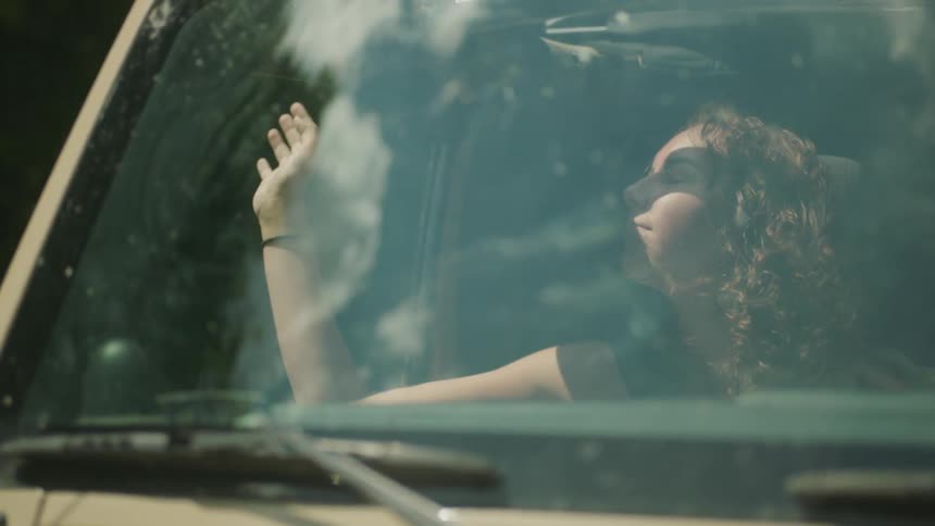 Woman riding in car feeling the wind on her hand and hair