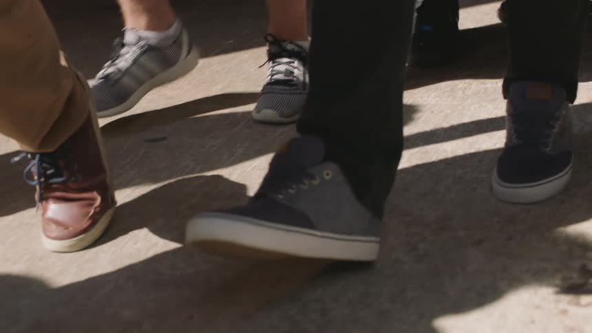 Feet walk on a sidewalk