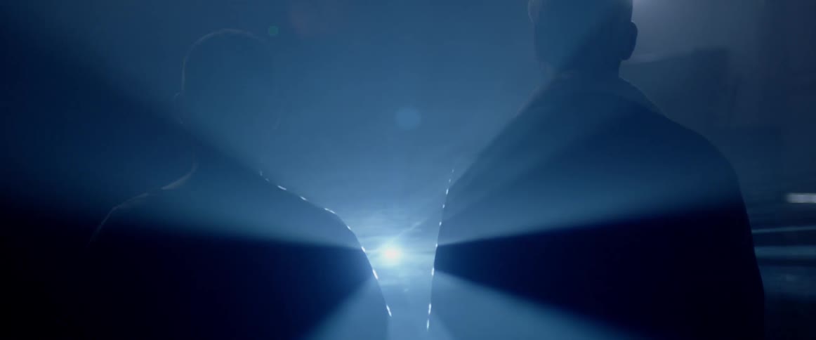 A bright light shines between two men