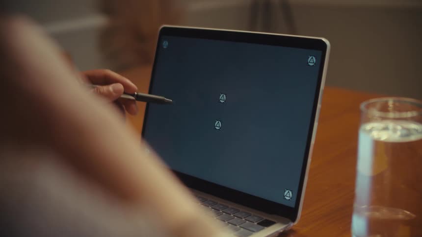 A person points with a pen to a laptop screen with tracking markers as another person uses the computer