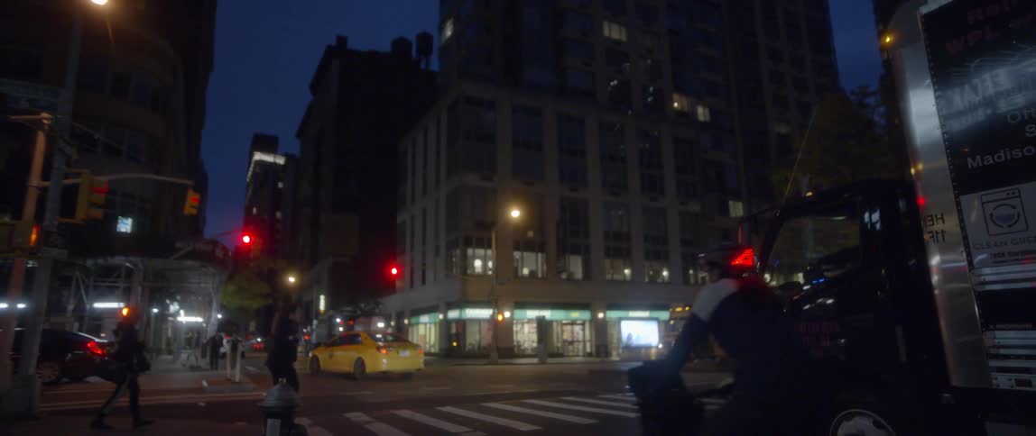 Pedestrians and vehicles navigate an intersection at night