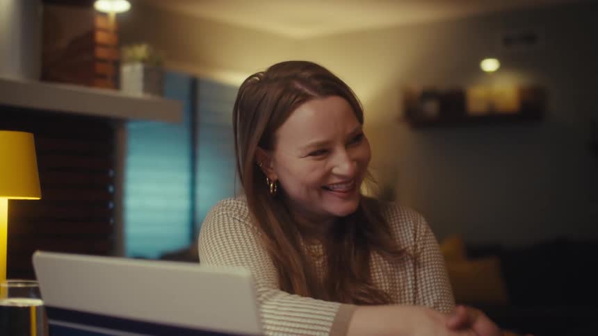 A friendly business consultant and her client shake hands in agreement during a meeting in a warmly lit home