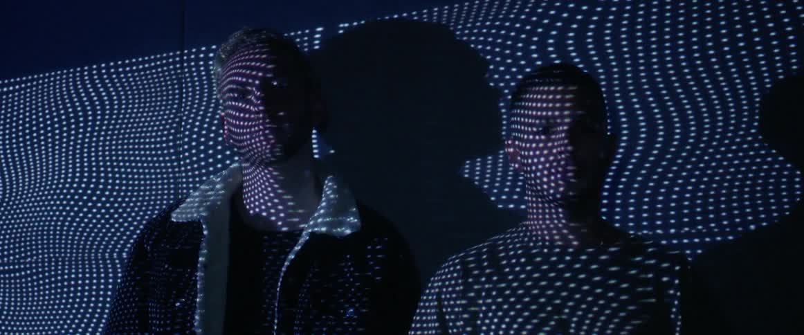 Wavy lines of dots are projected onto two young men