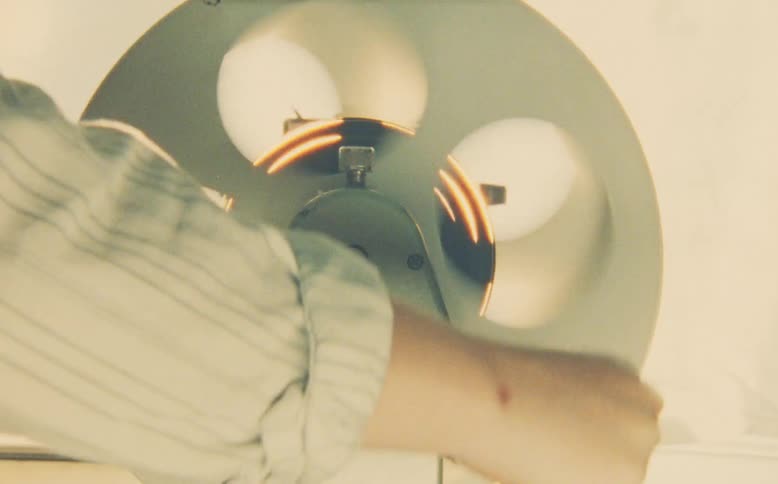 Close-up of a hand manually rewinding a vintage film reel on an old editing viewer