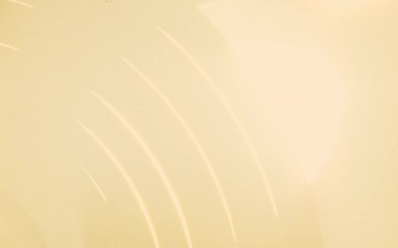 Close-up of a hand cranking a vintage film reel creating abstract light streaks