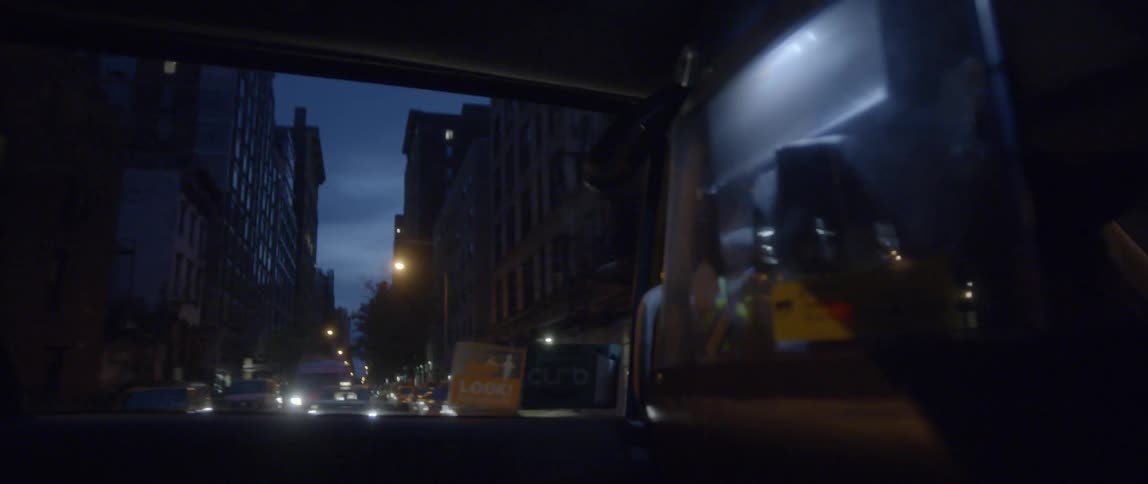 A vehicle drives on a city street at night